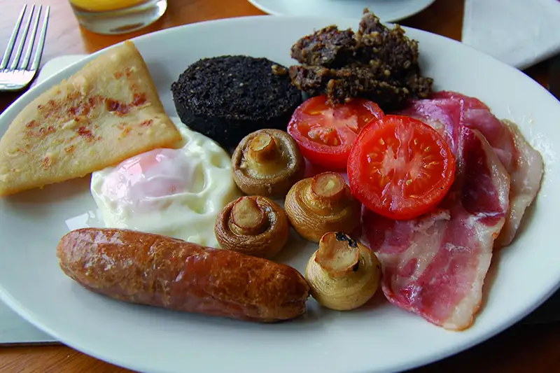 Assiette de petit-déjeuner écossais traditionnel avec saucisse, œuf, champignons, boudin noir, tomate et tattie scone