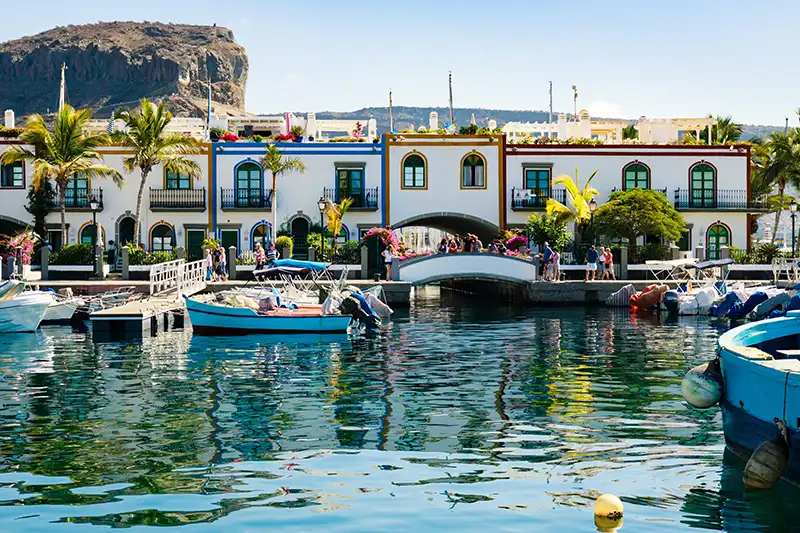 Vue sur le port coloré de Puerto de Mogán, avec des bateaux et des bâtiments colorés.