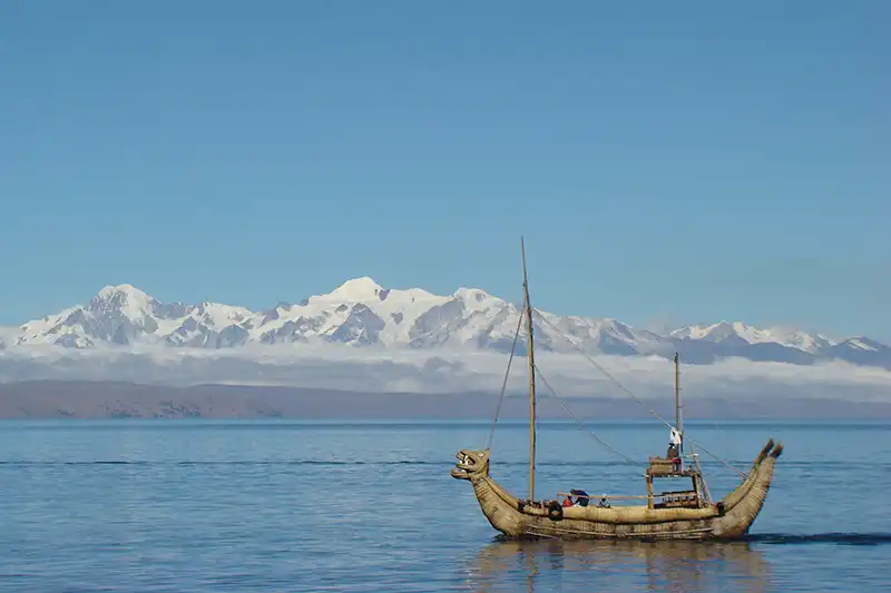 Navigation sur le lac Titicaca en Bolivie Bateau en roseau naviguant sur le lac Titicaca avec les Andes en arriรจre-plan
