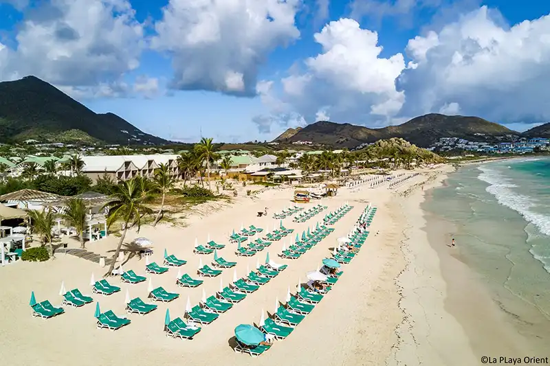 Orient Bay, l’une des plus belles plages de Saint-Martin Plage d’Orient Bay à Saint-Martin avec rangées de transats et parasols