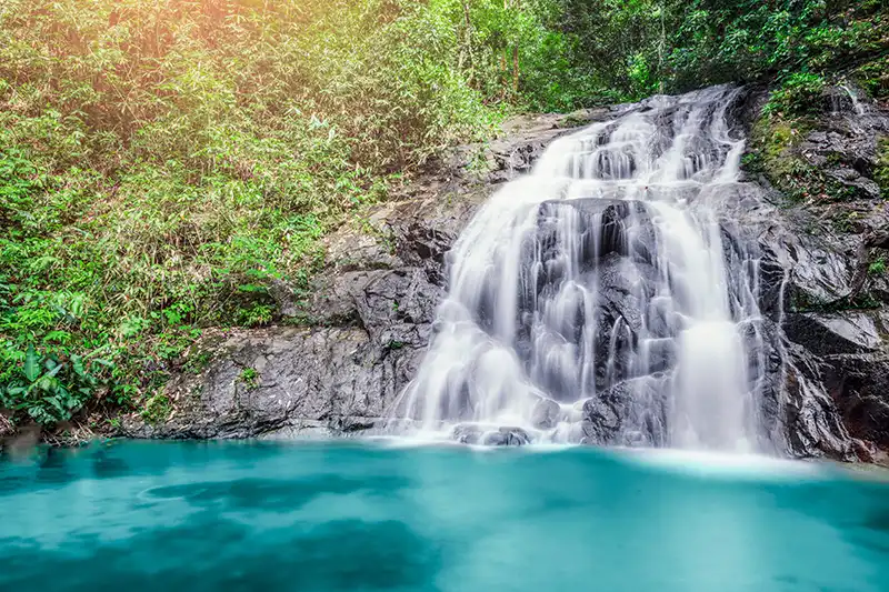 Cascade entourée de végétation tropicale en Thaïlande avec bassin d’eau turquoise
