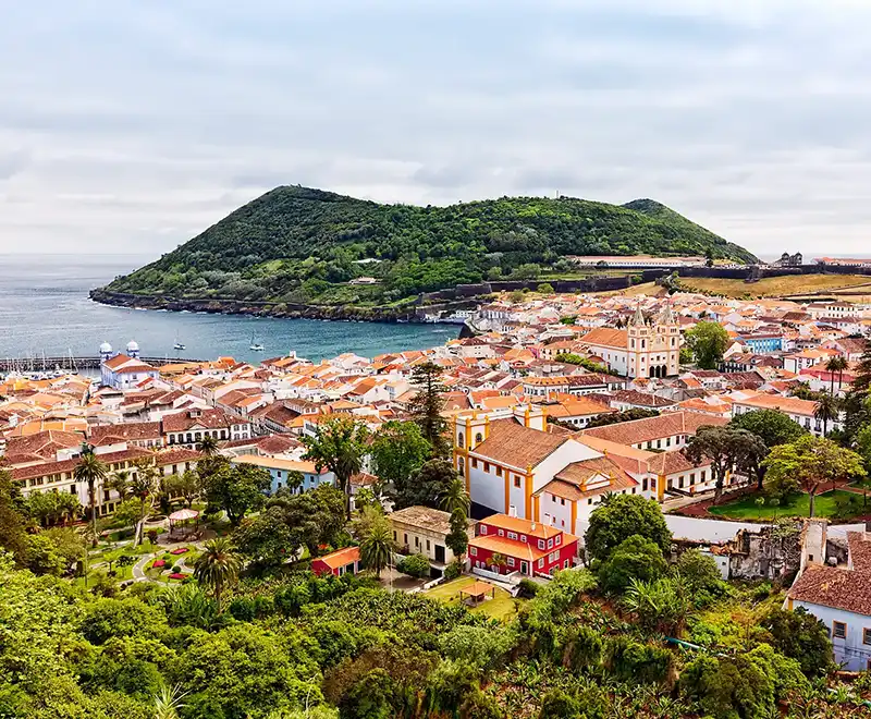 Vue panoramique sur une ville côtière des Açores avec maisons colorées et collines verdoyantes