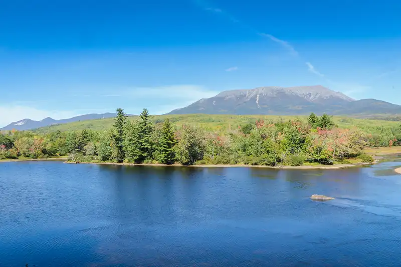 Lac bordé de forêts avec un massif montagneux en arrière-plan, dans le Maine