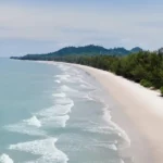 Plage de sable blanc bordée de végétation tropicale à Bornéo, en Malaisie