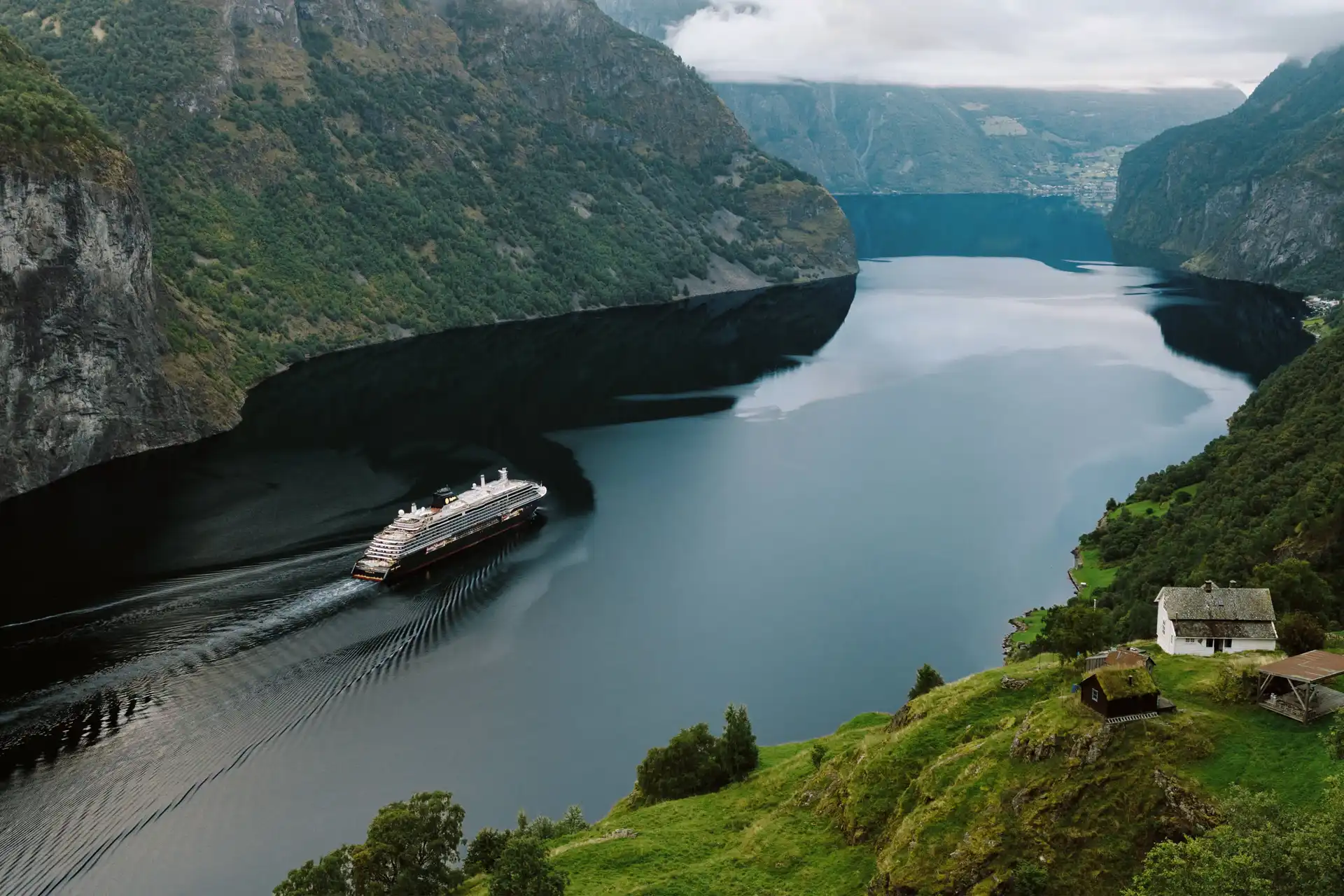 Explora Journeys – Croisières Europe du Nord 2027 Navire de croisière naviguant dans un fjord norvégien entouré de montagnes escarpées