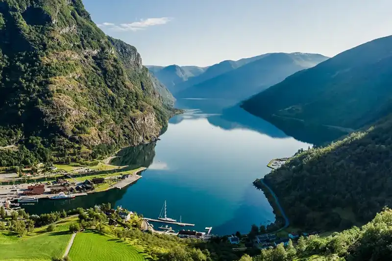 Fjord norvégien entouré de montagnes verdoyantes avec un village au bord de l’eau