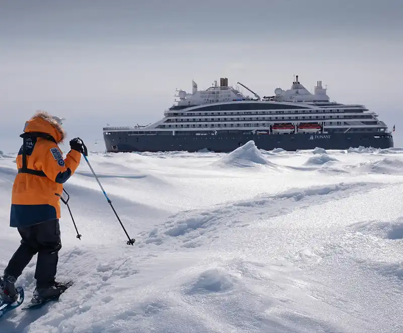 Le Commandant Charcot de PONANT dans la banquise, avec un explorateur à ski au premier plan